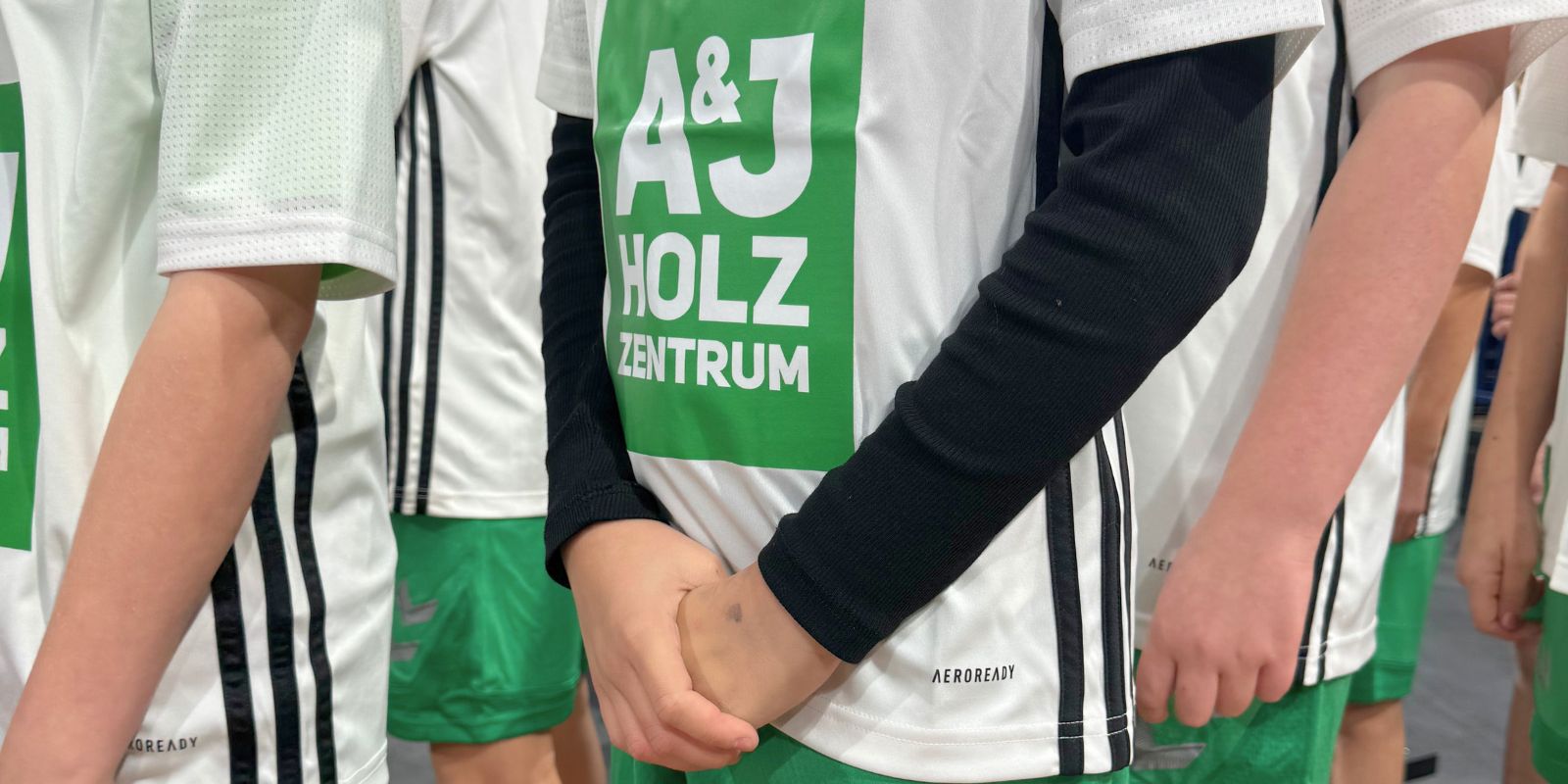 Ausschnitt von Oberkörpern von der Taille bis zur Brust der Einlaufkinder im A&J Trikot, die auf ihren großen Einsatz warten